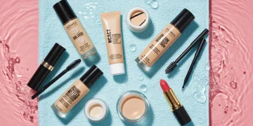 Seven essential waterproof makeup products for summer 2025, arranged on a blue towel